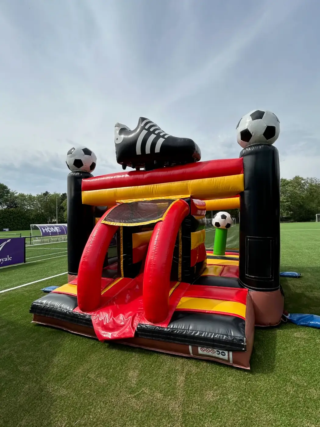 Rood met zwart springkasteel met voetbalthema op een voetbalveld, een vaste waarde om een springkasteel te huren voor een clubfeest in Brussel