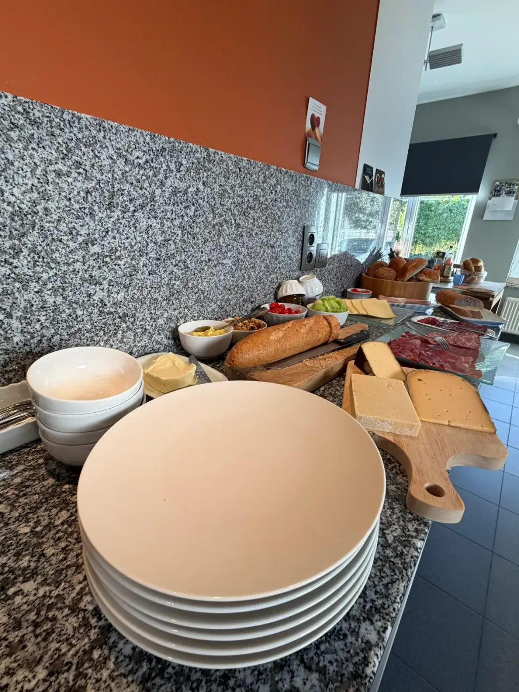 Stapel borden en kommen naast kaasplanken en stokbrood op een buffet, precies wat je nodig hebt om tafelgerei te huren voor een feest in Beveren