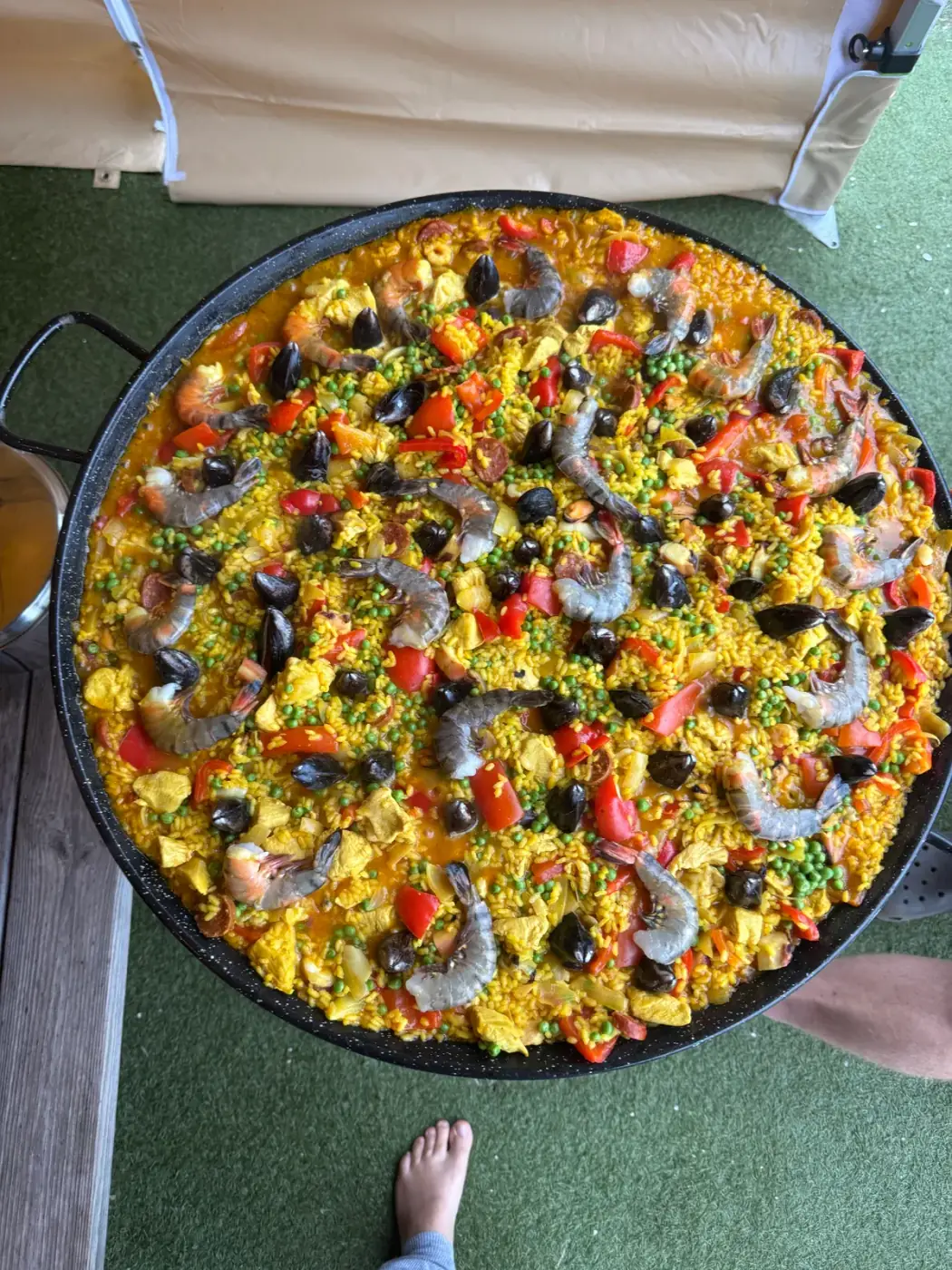 Grote paellapan vol paella met garnalen en mosselen onder een tent, handig om tafelgerei te huren voor een groot gezelschap in Ranst