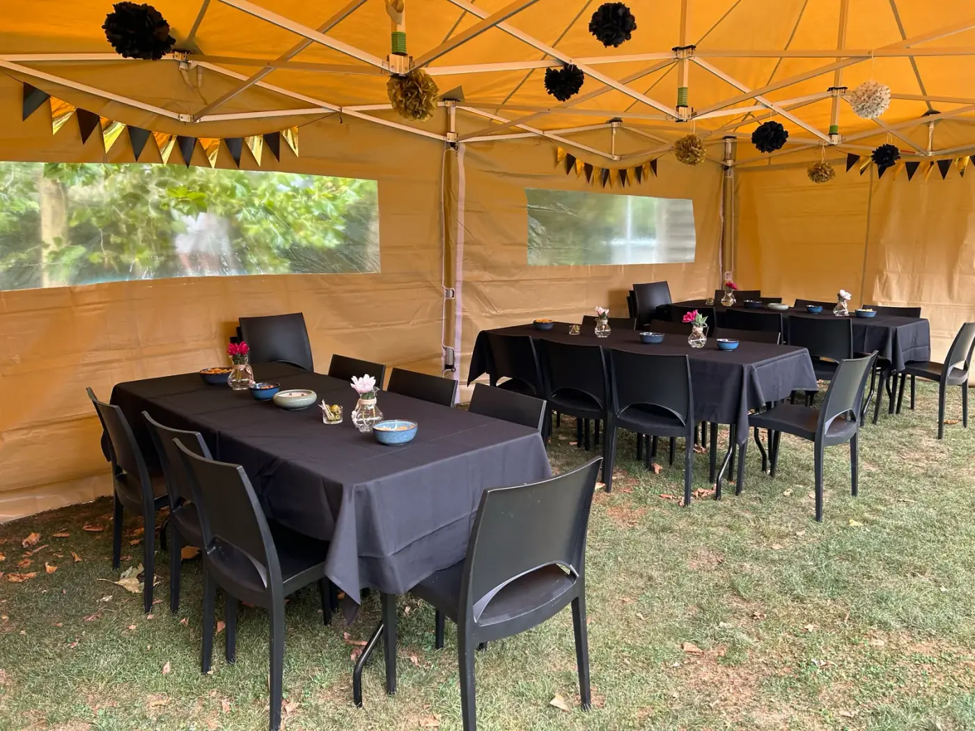 Beige vouwtent met zwart gedekte tafels, zwarte stoelen en slingers in de tuin, klaar om een tent te huren voor een verjaardagsfeest in Deurne