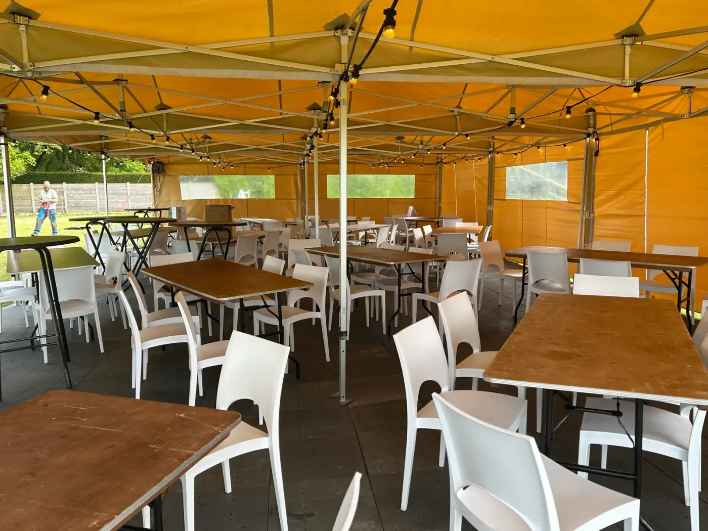 Beige vouwtent van binnenuit met witte stoelen rond houten klaptafels, een complete opstelling om een tent te huren voor een zittend feest in Schilde
